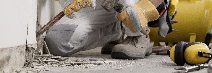 Ein Handwerker entfernt Putz von einer Wand.